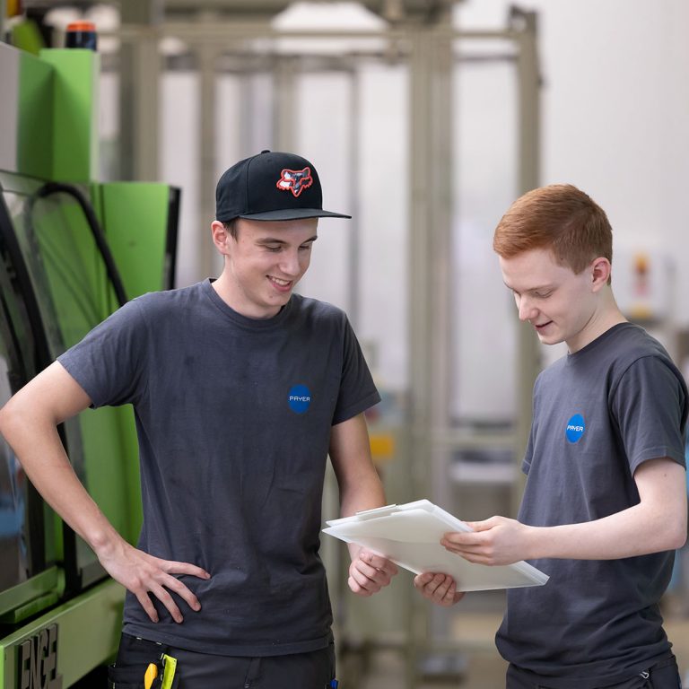 The picture shows two plastics engineering apprentices in the production environment of PAYER Austria.