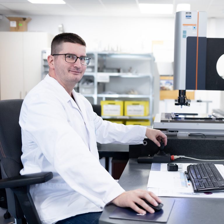 The picture shows a colleague sitting in front of a testing machine in our quality deparment.