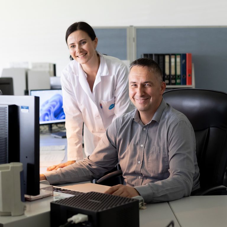 The picture shows two employees sitting in front of a computer in the tool construction.